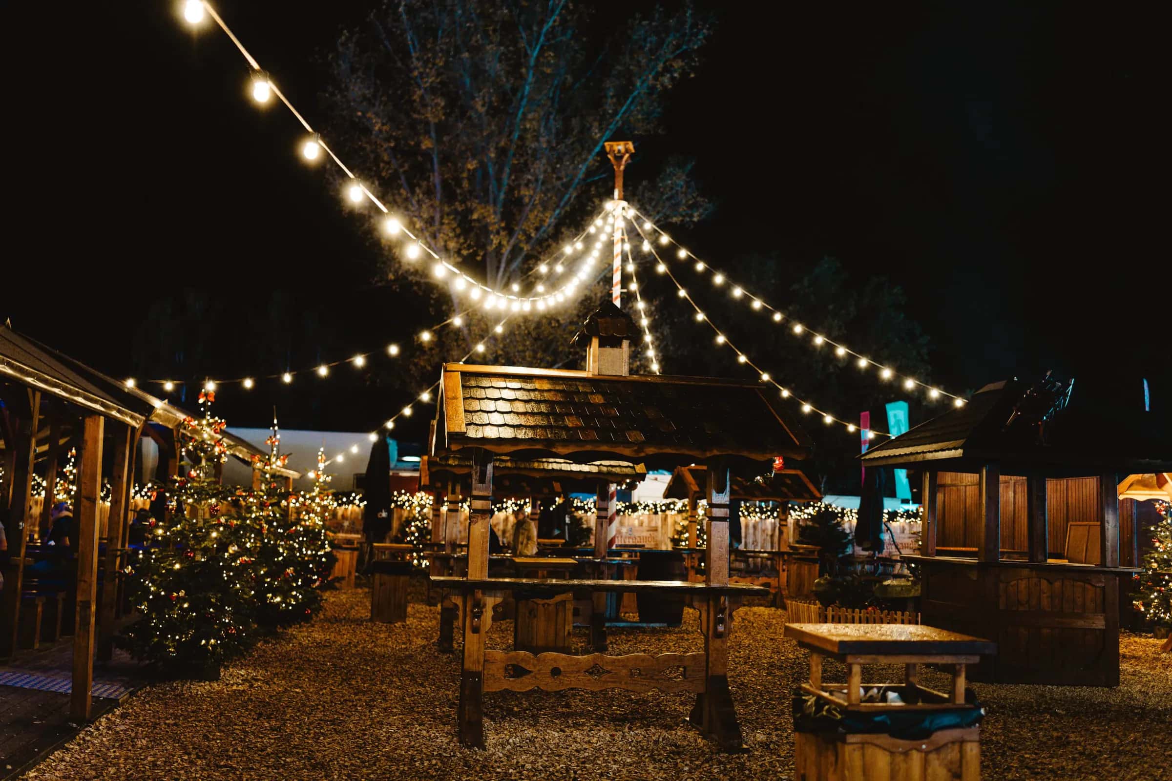 Mercado navideño de noche con casetas de madera iluminadas
